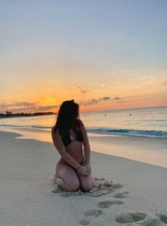 a woman kneeling down in the sand at the beach