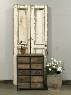 an old cabinet and flower pot sit next to each other in front of a white painted door