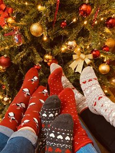 two people are sitting in front of a christmas tree with their feet up on the ground