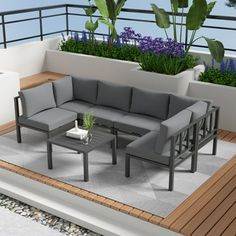 an outdoor living area with grey furniture and plants