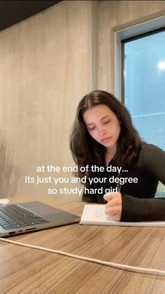 a woman sitting at a table with a laptop and notepad in front of her