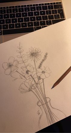 a drawing of flowers in a vase next to a laptop