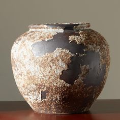 a brown and white vase sitting on top of a wooden table