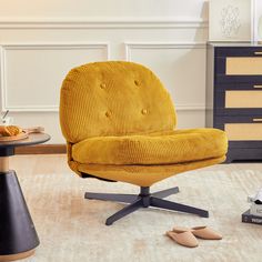 a yellow chair sitting on top of a white rug next to a table and dresser