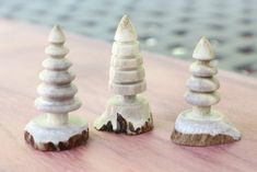 three small wooden sculptures sitting on top of a wood table next to eachother