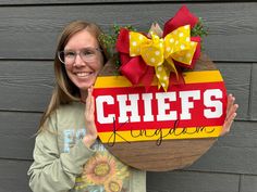 a woman holding up a sign that says chiefs on it with a bow and sunflowers