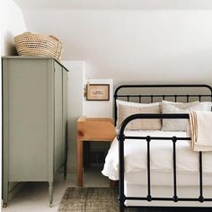 a bedroom with a metal bed frame and white linens on the pillows, next to a dresser