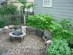 an outdoor fire pit surrounded by plants and rocks