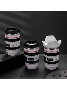 three camera lens coffee mugs sitting on top of a table next to each other