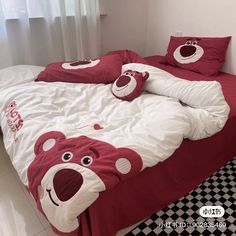 a bed with red and white comforters, pillows and teddy bears on it's head