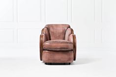 a brown leather chair sitting in front of a white wall