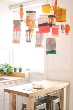 several paper lanterns hanging from the ceiling above a kitchen table with stools and bar stools