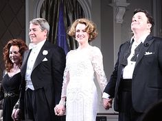 three people standing next to each other in formal wear and tuxedos on stage