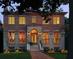 a large brick house with many windows and steps leading up to the front door at night