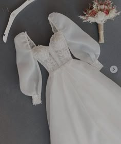 the dress is laying on the floor next to a flower and hair comb, which has been pinned in place