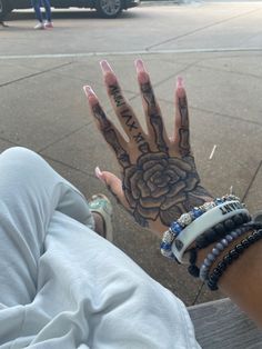 a person's hand with tattoos and bracelets on it, next to a car