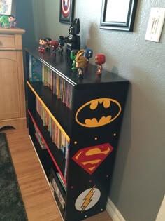 a batman bookcase is in the corner of a room next to a dresser with toy figurines on it