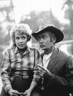 black and white photograph of a man sitting next to a woman wearing a cowboy hat