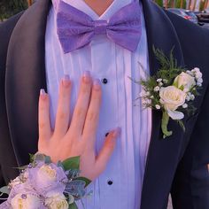 a close up of a person wearing a suit and tie with flowers on his lapel