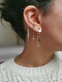 a close up of a person wearing some kind of earring with stars and moon on it