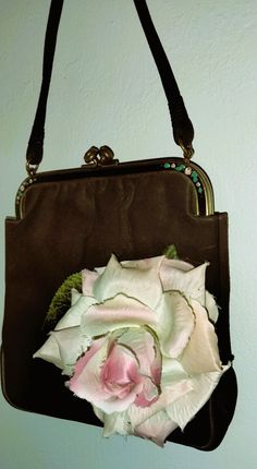 Unique and feminine 1940s Rosenfeld brown clutch with a pink rose embellishment. This bag is in very good condition, the satin lining is pristine and marked with the Rosenfeld logo inside. It is a soft, suede-like velveteen fabric in a rich chocolate-brown color. The frame at the top has tiny hand-painted roses and it has a standard clasp. An adorable addition to your collection, this purse is approximately 7.5" in height by 7" wide at the bottom, and the strap is 13" long in total. Turn some he Brown Clutch, Chocolate Brown Colour, Hand Painted Roses, Tiny Hand, Pink Rose, Purses And Handbags, Top Handle Bag, Unique Designs, Accessory Gift