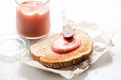 a sandwich with ketchup on it next to a jar of sauce and a spoon