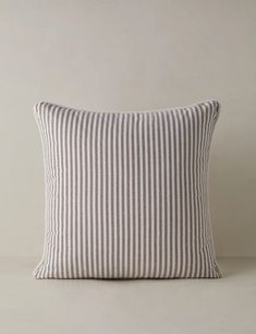 a striped pillow sitting on top of a white table next to a brown and white wall