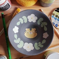 a bowl with hello kitty painted on it next to paintbrushes and other crafting supplies