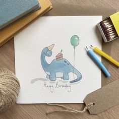 a card with an elephant holding a birthday cake on it, next to some crayons and twine