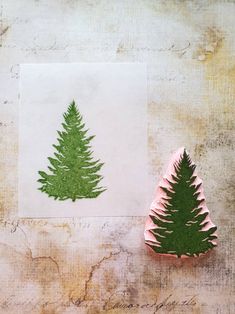 two small green trees sitting next to each other on top of a piece of paper