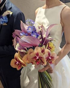 the bride and groom are holding bouquets of orchids in their hands as they stand next to each other