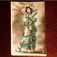 an old photo of a woman in a dress with flowers on her head and branches around her neck