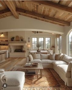 a living room filled with white furniture and lots of wooden beams on the ceiling,