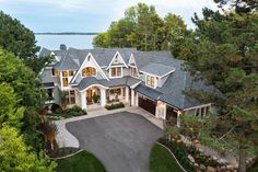 an aerial view of a large house with lots of trees and water in the background