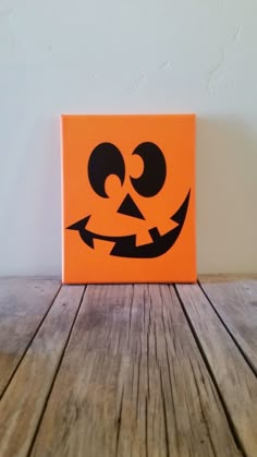 an orange box with a black face painted on the front and bottom, sitting on a wooden table