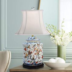 a table lamp sitting on top of a wooden table next to a bowl and vase