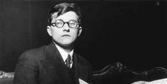 black and white photograph of a young boy in glasses sitting at a desk with an open book