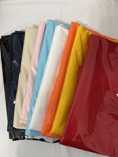 various colors of plastic bags lined up on a white tableclothed surface with one bag in the middle