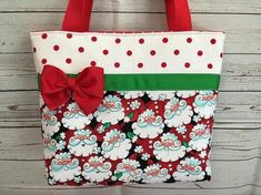 a red and white tote bag with a bow on the front is hanging from a hook