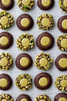 chocolate cookies with peanut butter frosting and pistachio sprinkles on a baking sheet