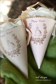 two paper cones are sitting on a green towel with the words happy easter printed on them