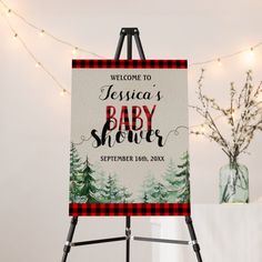 a welcome sign for a baby shower is displayed on a easel with lights in the background