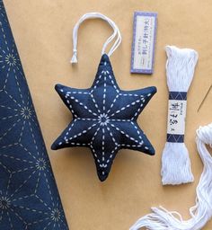 a blue star ornament next to some white thread and other crafting supplies