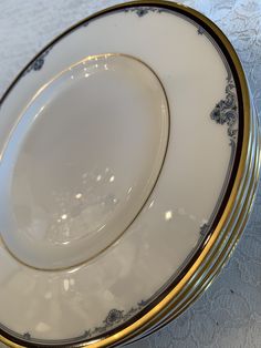 two white and gold plates sitting side by side on a tablecloth covered table top