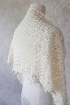 a white knitted shawl on a mannequin