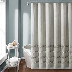 a white bath tub sitting under a window next to a shower curtain in a bathroom