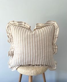 a white and brown striped pillow sitting on top of a stool