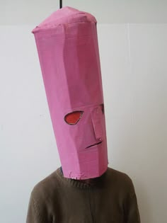 a person wearing a pink paper bag over their head with a red eye on it