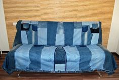 a couch covered in blue jean fabric sitting on top of a hard wood floor