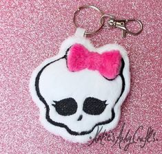 a skull key chain with a pink bow on it's head and black eyes